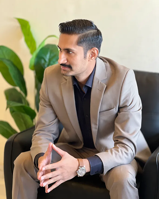 Hasnain Ali seated in a tan suit